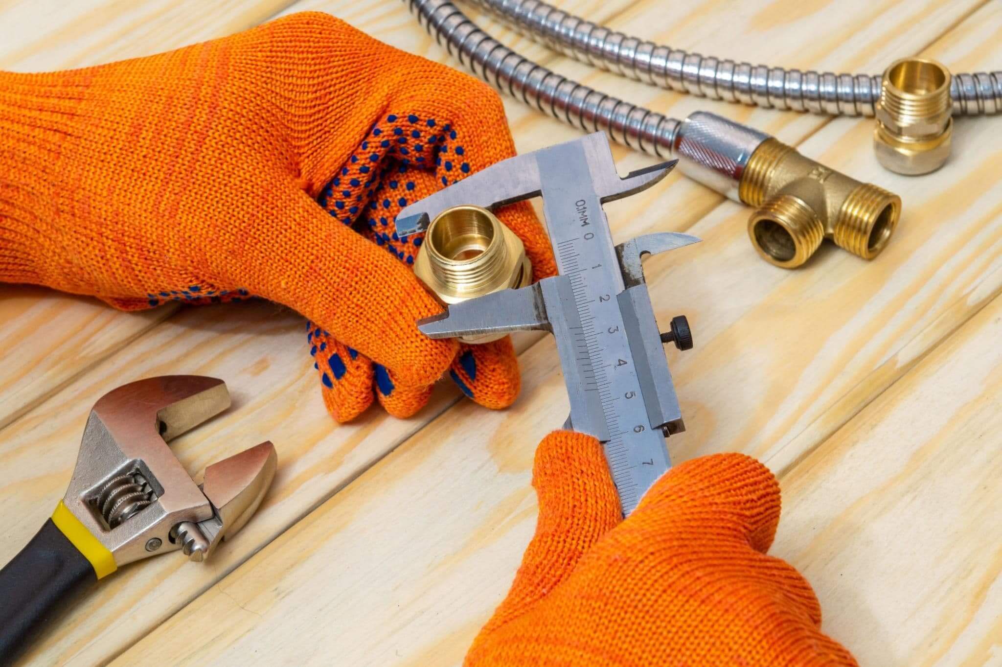 Imperial metric pipe fittings guide with hand tools measuring brass fittings on wooden surface.