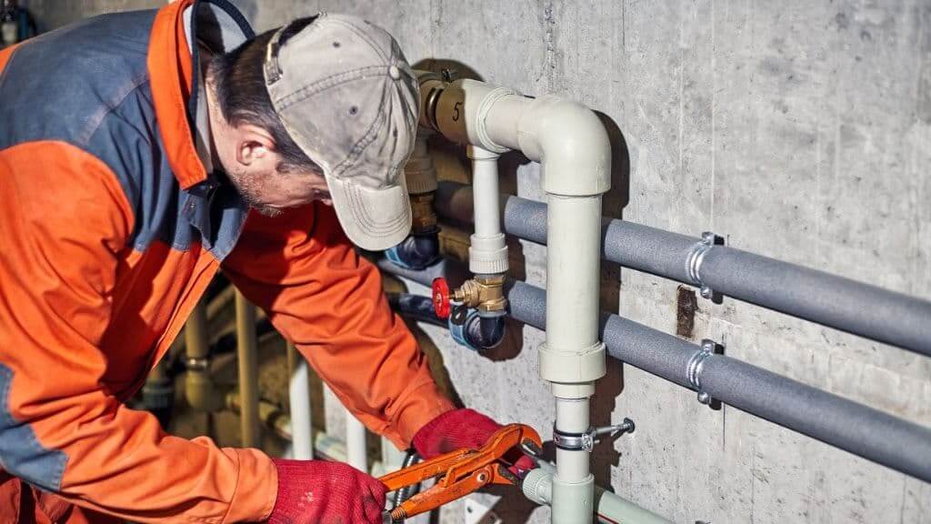 Worker addressing common industrial pipe installation mistakes during a complex piping setup.