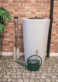 City Just Water 210L Water Butt - White Marble Effect next to a watering can and garden spade on a stone patio.