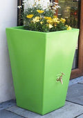 Apple Cambridge 90L Water Butt Planter - Apple Green with flowers outside a house.