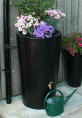 Black City Water Butt Planter - 180L Decorative Water Tank with flowers and watering can.