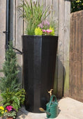 Black Metropolitan 255L Water Butt Planter - Decorative Tank with floral plants and watering can.