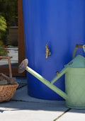 Blue Big City Water Butt Planter - 380L Blue Capacity next to a green watering can and basket.