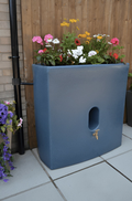 Blue Marble Oasis 375L Water Butt Planter - Blue Marble Effect with flowers on top in a modern garden setting.