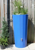 Metropolitan 255L Water Butt Planter - Blue Decorative Tank with plants against a wooden fence.