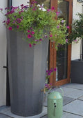 Millstone Metropolitan 255L Water Butt Planter - Stone Effect with vibrant flowers and decorative watering can.