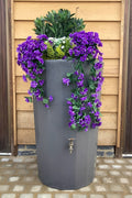 Millstone Midi Metropolitan Water Butt Planter - 165L Stone Effect with flowers and greenery.