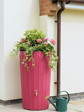 Pink Cosmo 200L Water Butt Planter - Pink Marble Effect with vibrant flowers and greenery beside a green watering can.