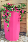 Midi Metropolitan 165L Water Butt Planter - Pink filled with vibrant flowers and greenery