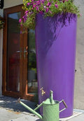 Purple Big City Water Butt Planter - 380L Capacity with flowers and watering can in a garden setting.