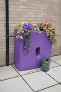Purple Oasis 375 Litre Water Butt Planter - Purple MDPE with colorful flowers and a green watering can.