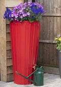Red Cosmo 2-in-1 Water Butt Planter - Red 200L with flowers in top and green watering can beside it.