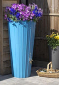 Cosmo 200L Water Butt Planter - Sky Blue Decorative Tank with vibrant flowers on top in a garden setting.