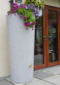 White Marble Big City Water Butt Planter - 380L Capacity with colorful flowers near a wooden door.