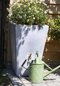 Cambridge 90L Water Butt Planter - White Marble Effect with flowers and green watering can.