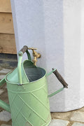 White Marble Midi Metropolitan Water Butt Planter - 165L next to a vintage green watering can.